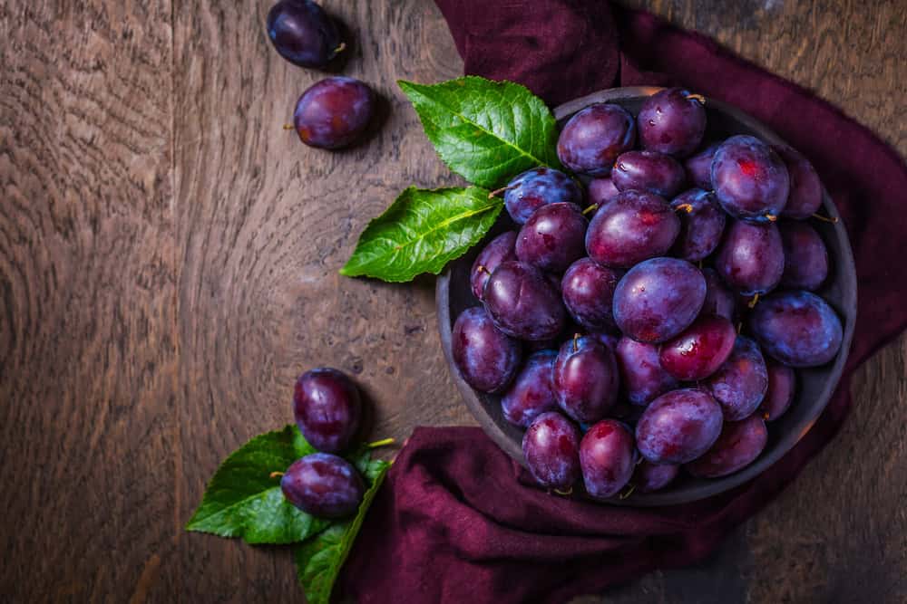 frische Pflaumen auf Holzhintergrund Pflaumenkorb